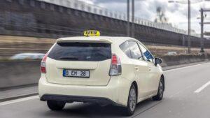 מונית בגוון קרם עם שלט TAXI על הגג נוסעת בכביש בפורטוגל